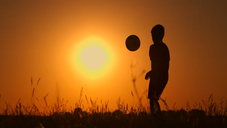 Silhouette-Eines-Jungen,-Der-Bei-Sonnenuntergang-Fußball-Spielt.-Ein-Junge-Jongliert-Bei-Sonnenuntergang-Auf-Dem-Feld-Mit-Einem-Ball.